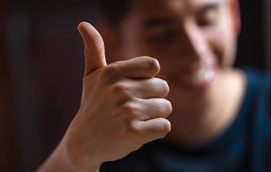 a smiling man gives a thumbs-up